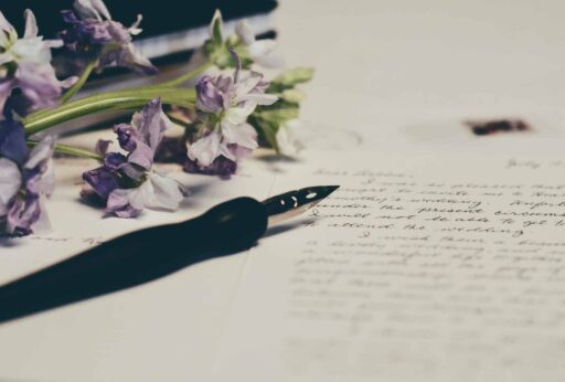 Image of ink pen, next to flowers, over a written letter