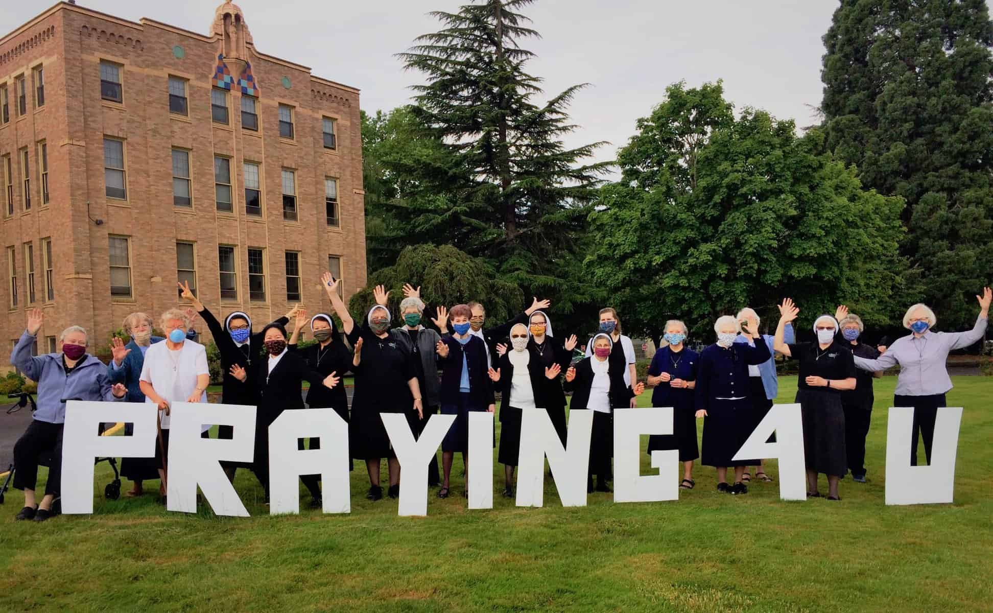 Sisters behind large cut out of "Praying 4 U"