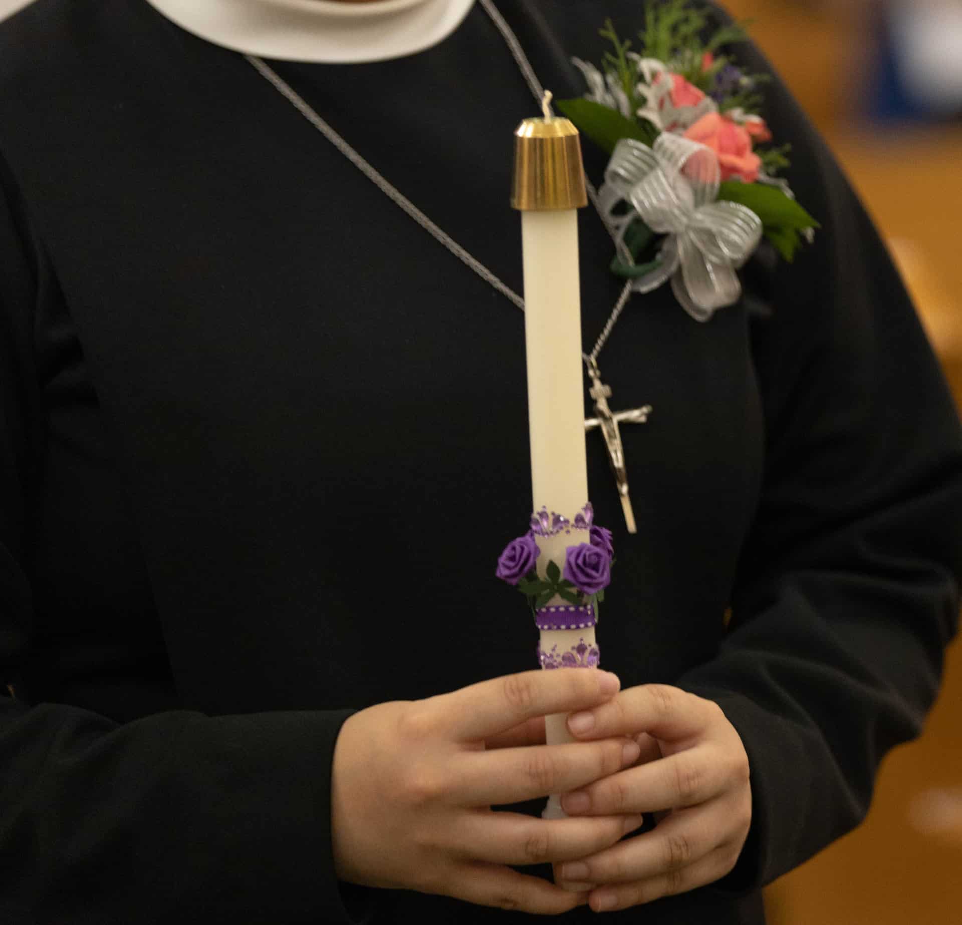 A Sister holding a candle during Mass