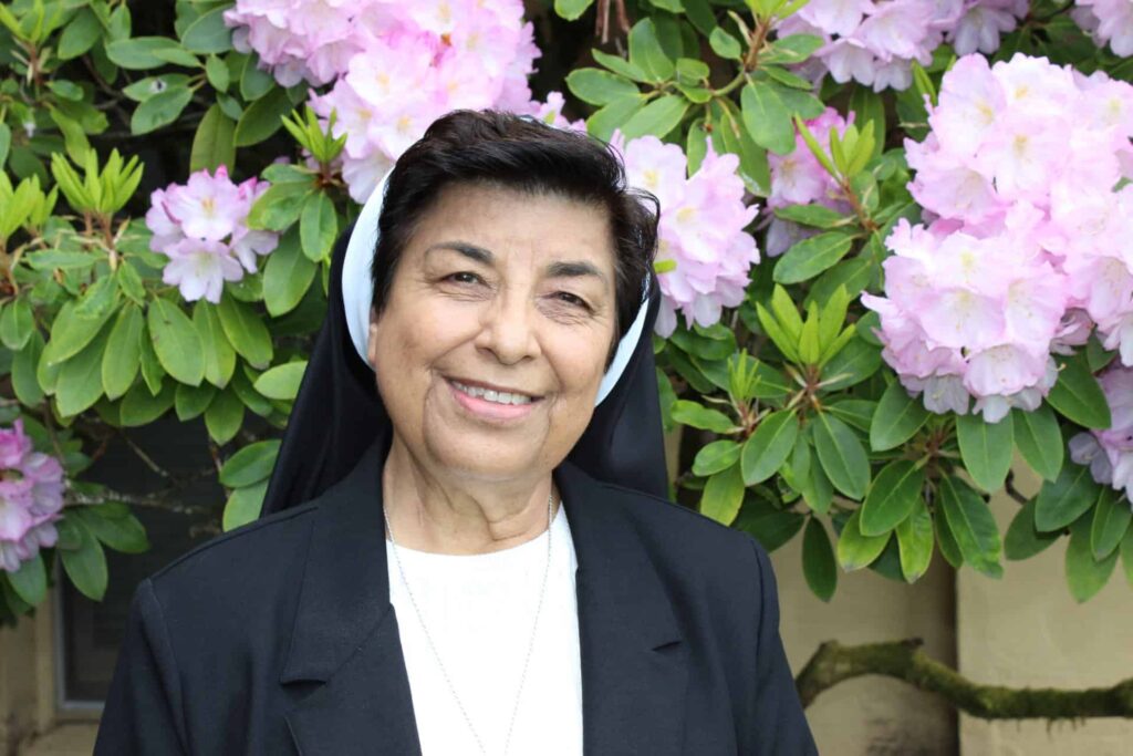 Sister M. Juanita Villareal in front of floral garden