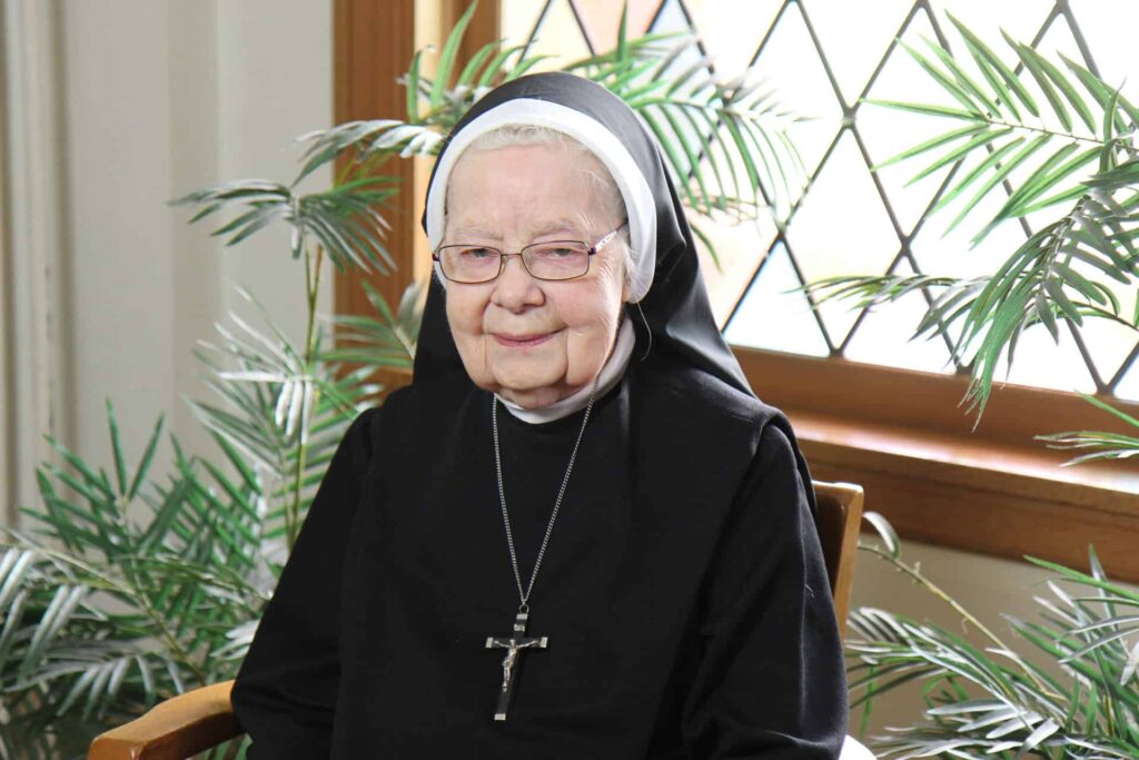 Sister Agnes Marie Vandecoevering in front of the stain glass window