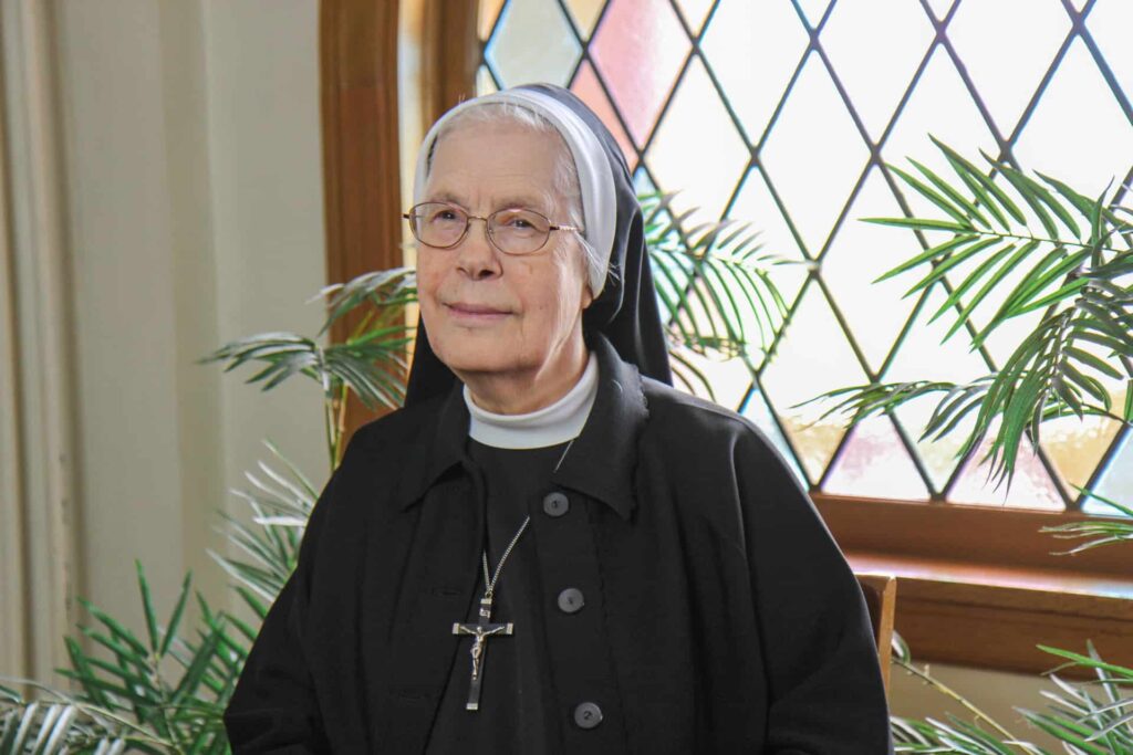 Sister Anne Vandecoevering in front of a stain glass window