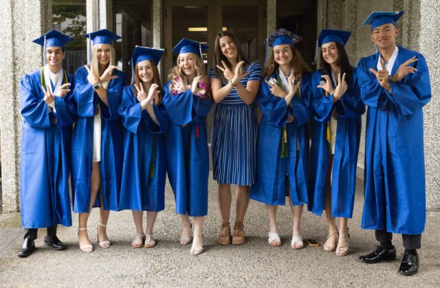 Graduates in cap and gown, with V C hand initials