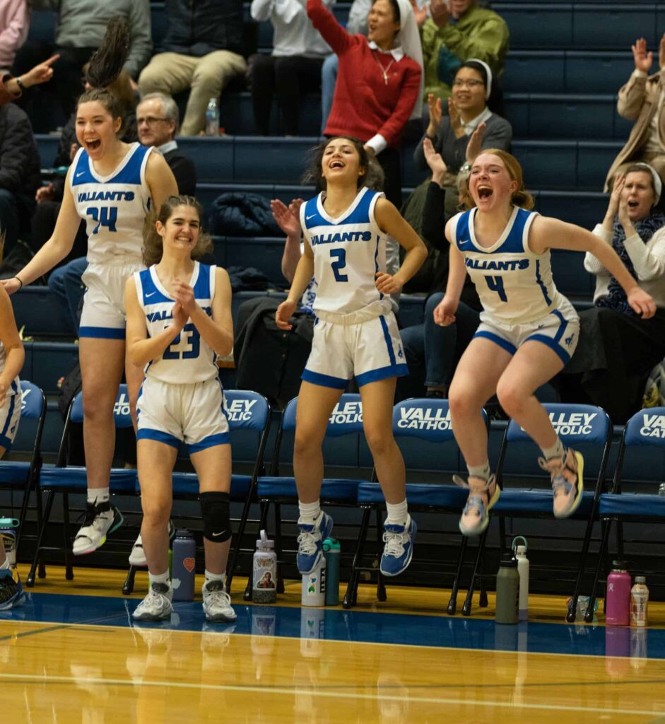Girls basketball team cheering, excited on sideline