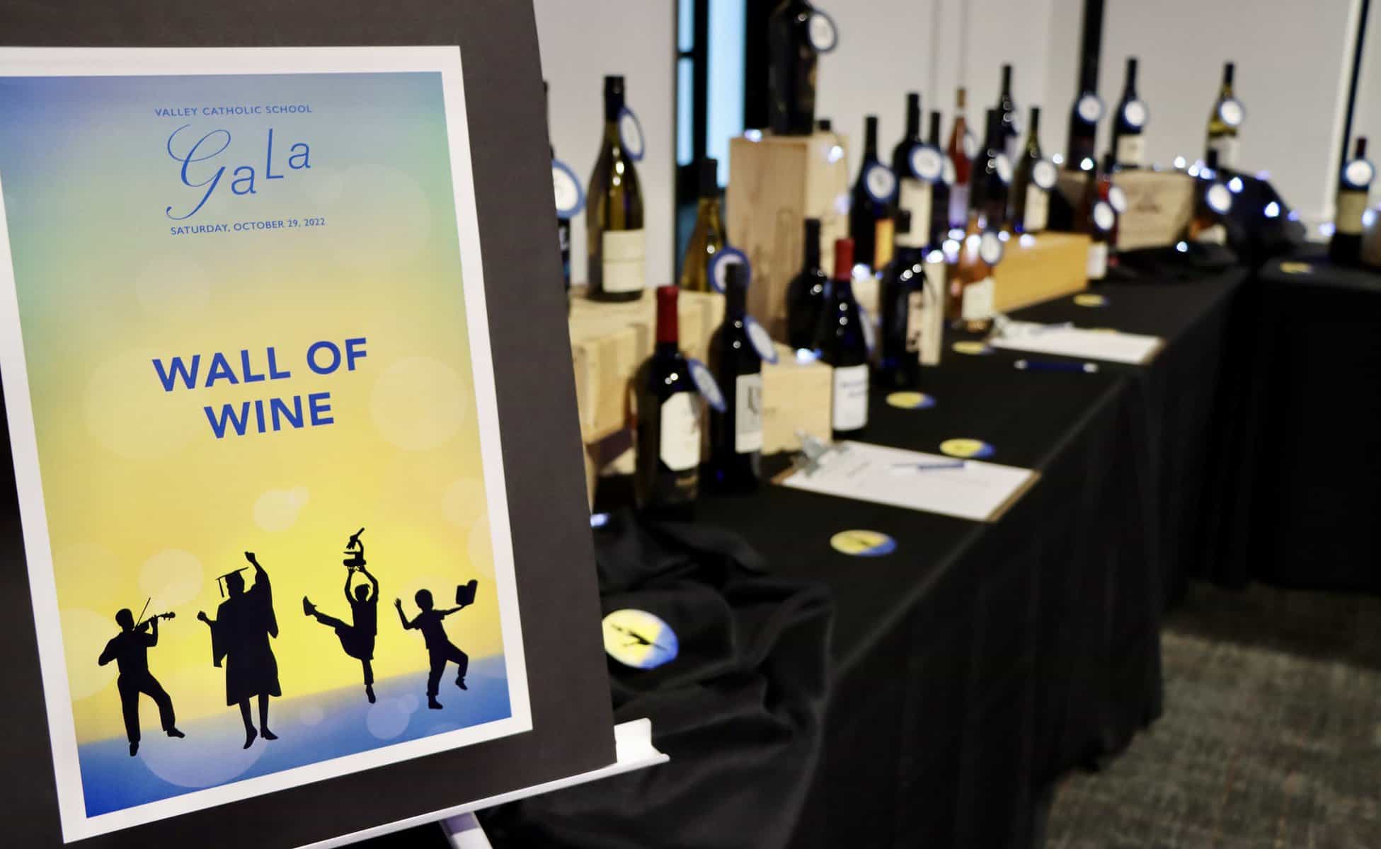 Wall of wine image with tables holding bottles of Gala wine