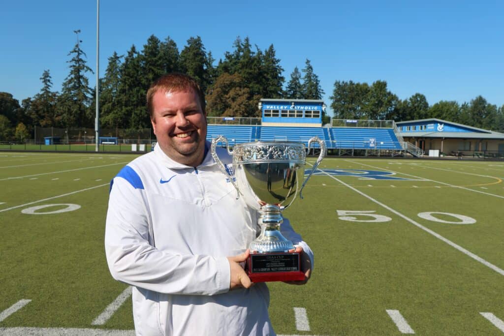 Patrick Chapman holds the OSAA Cup on the football field