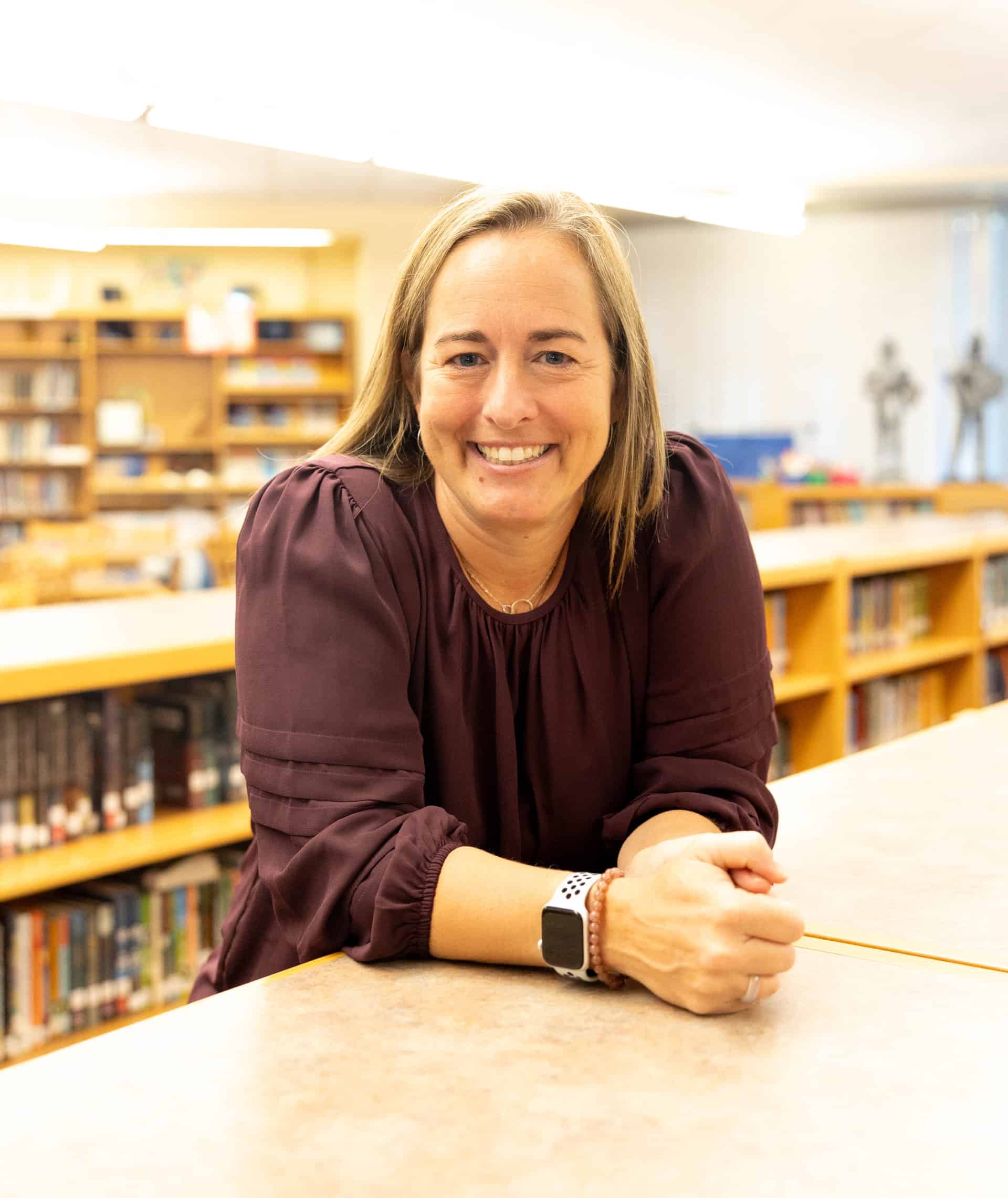 Dr. Sara Bruins, V C H S Principal, resting arms on a bookshelf