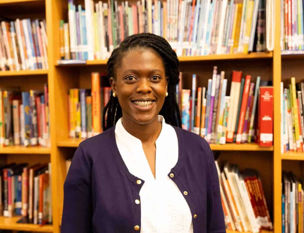 Yvonne, V C E S Principal, in front of book shelves
