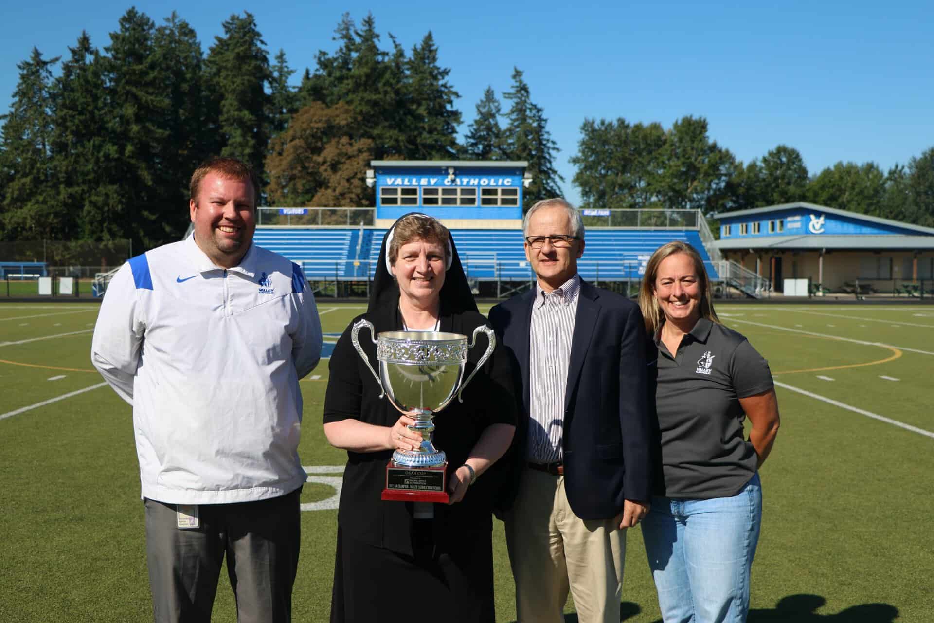 Administrators with O S A A Cup; Left to Right: Patrick Chapman, Sister Adele Marie Altenhofen holding the O S A A Cup, John Matcovich, and Dr. Sara Bruins