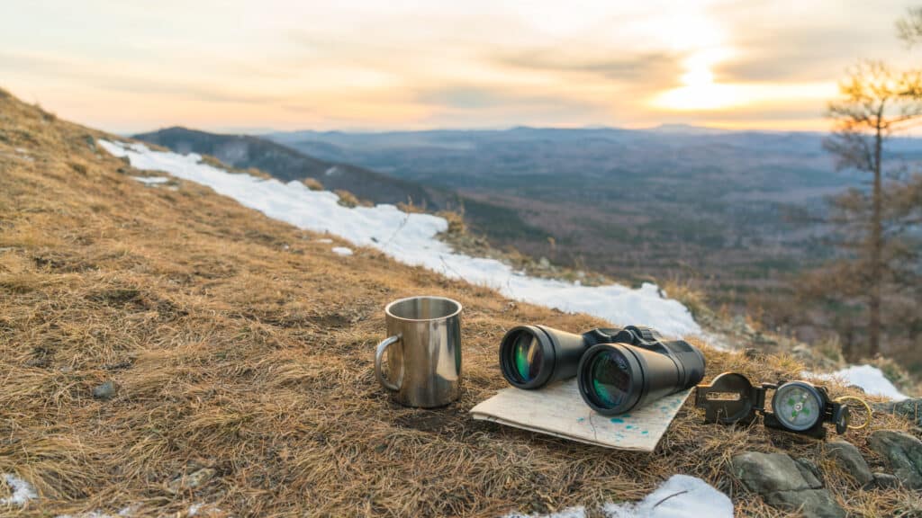 Binoculars,map,compass,and,mug,on,the,background,of,nature
