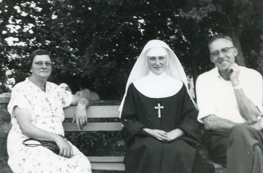 Sr. Marcella sitting on a bench with her parents