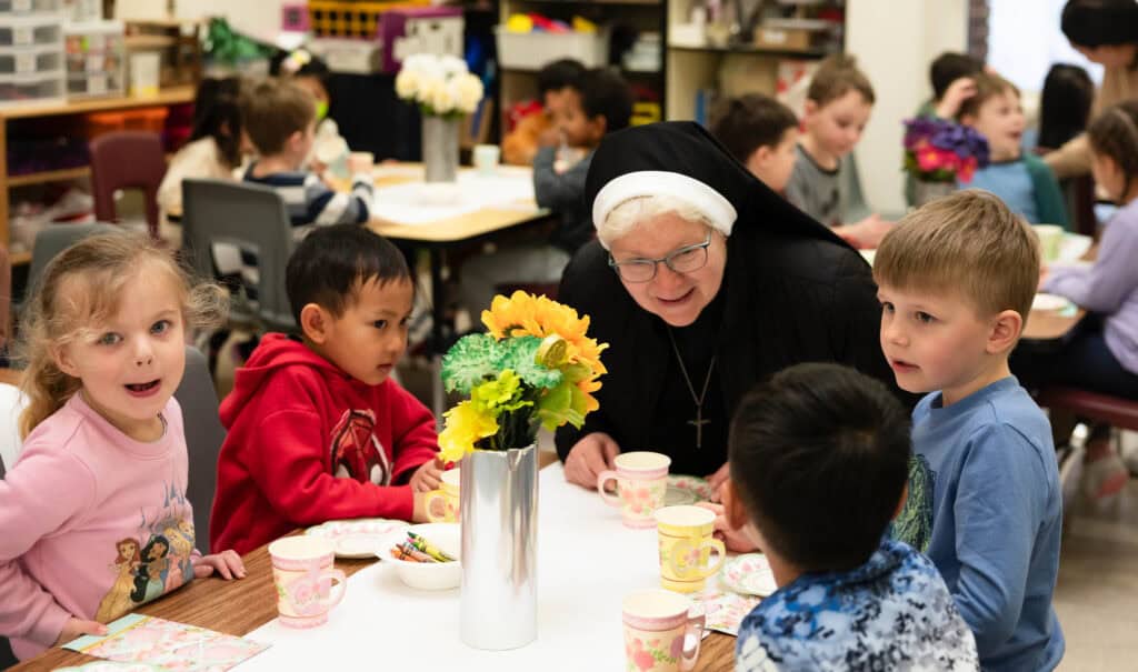 Sister Michael Francine enjoys tea with four early learning school students