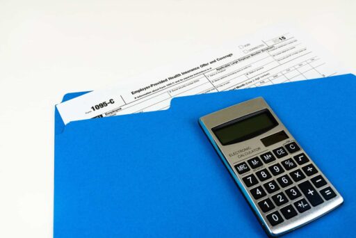 Blue folder holding 1095-c tax form with calculator