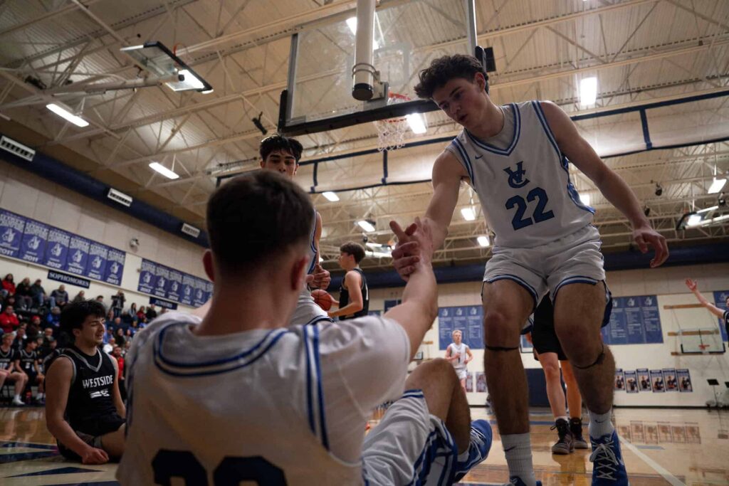Valiant boys basketball game vs Westside Christian; teammates assisting a player up from fall