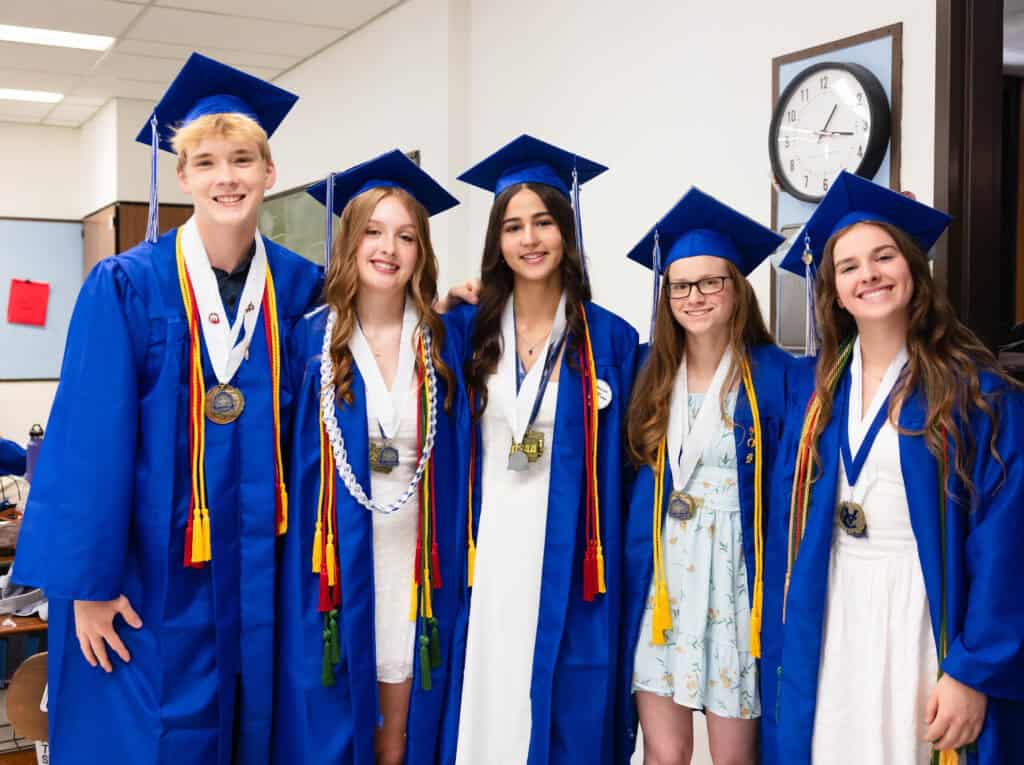 VCHS graduates posing in cap and gown with medals around their necks