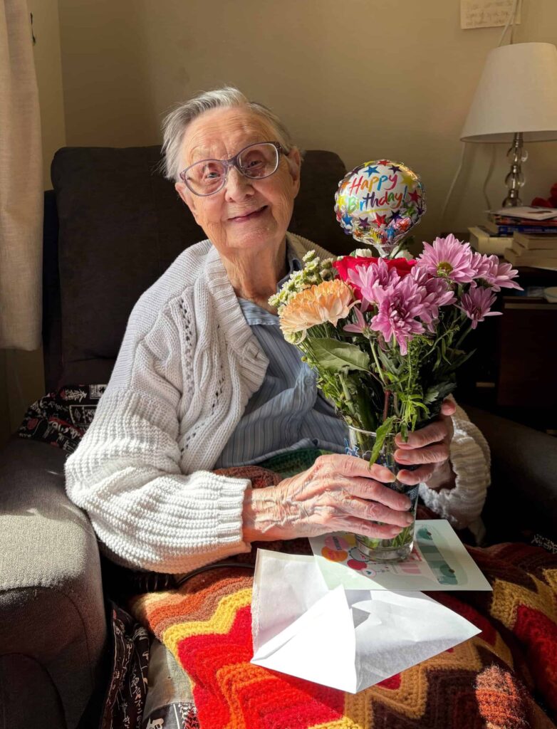 Florence Giddings Weber '41 on her 103rd birthday. Sitting in a chair with a bouquet of flowers