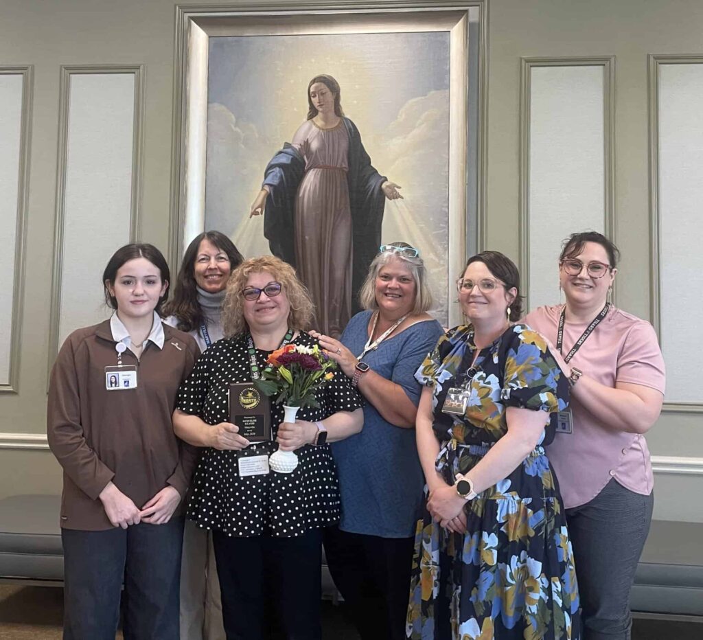 Jacqueline “Jackie” Illanes with the team. She holds her employee of the month plaque and flowers.