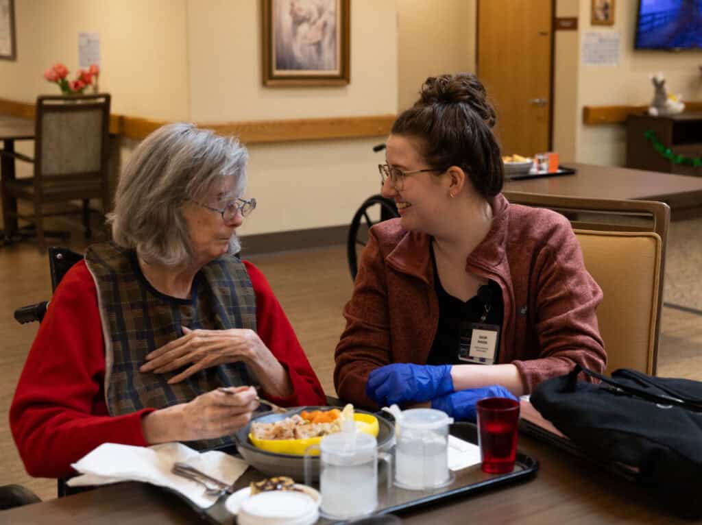 Resident having lunch with nurse web slider