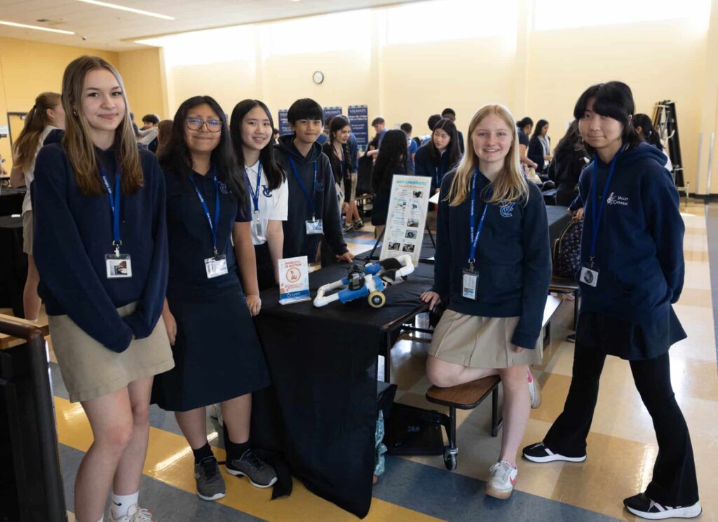 Panel of STEM students posing at table with presentation