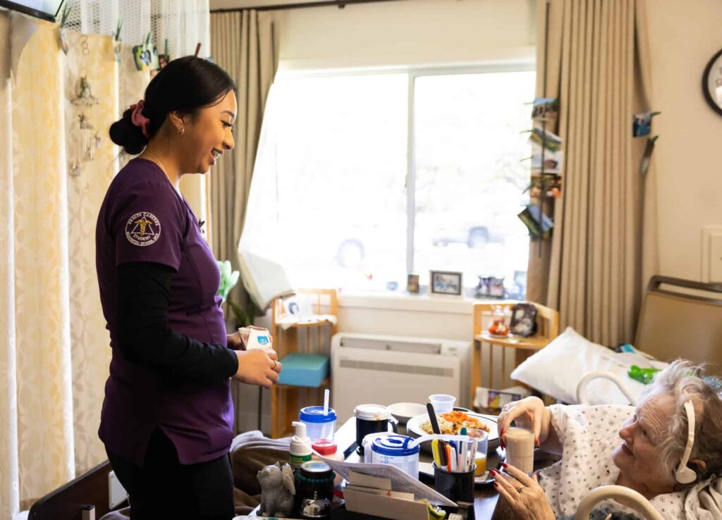 Student assisting a resident with her meal at bedside