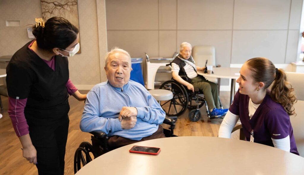 Two students talking with a Maryville resident at table side