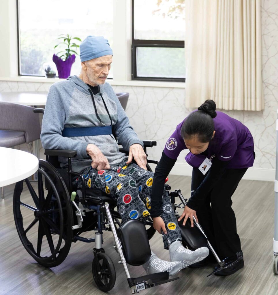 Student assisting a resident into his wheelchair