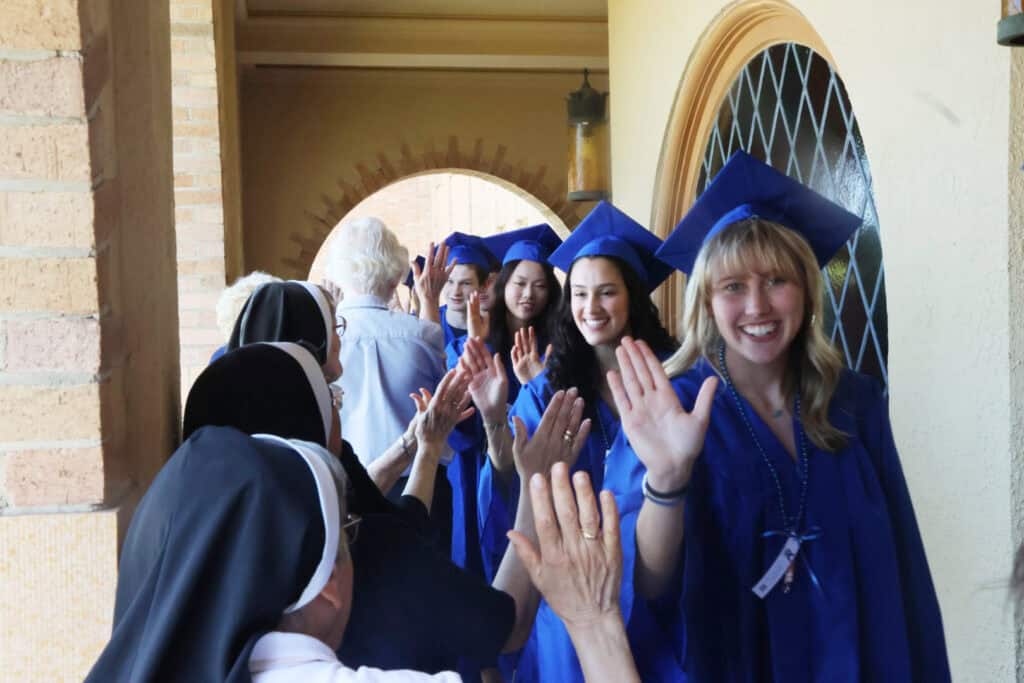 Sisters high five graduates during senior walk
